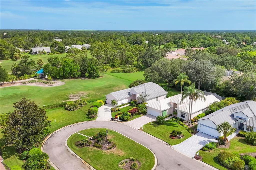 An aerial view shows several suburban houses situated along a curved street and golf course — 7916 HAMPTON COURT, UNIVERSITY PARK, FL