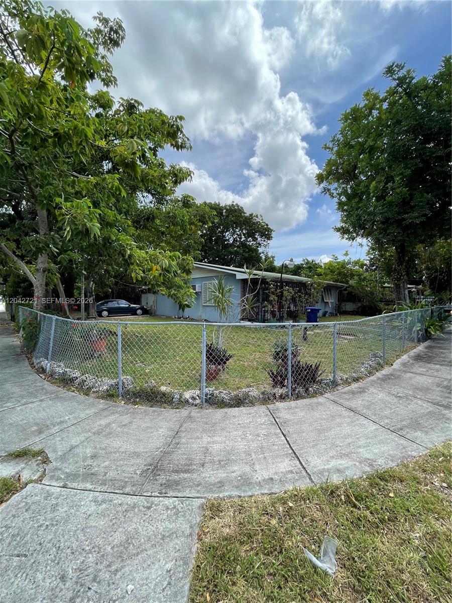A single-story house with blue siding sits behind a chain-link fence on a corner lot — 1797 NW 113th Ter, Miami FL 33167, MIAMI, FL