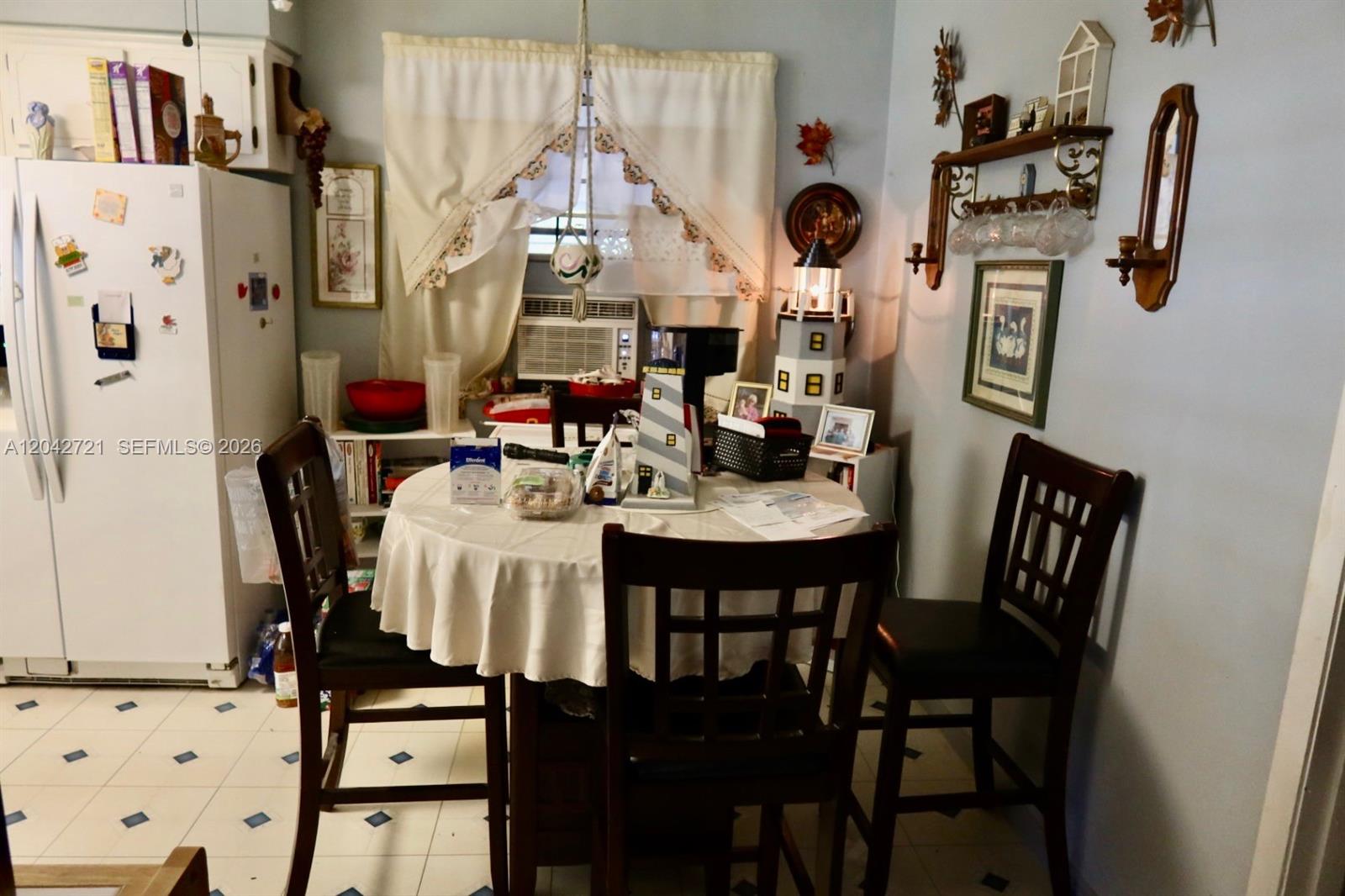 A kitchen features a round dining table, three chairs, a refrigerator, and nautical-themed decor — 1797 NW 113th Ter, Miami FL 33167, MIAMI, FL