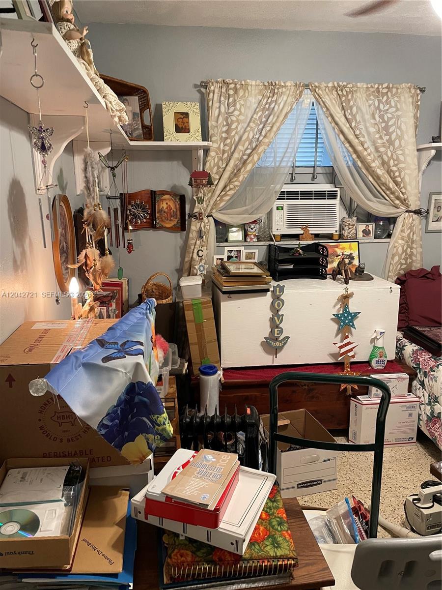 A cluttered bedroom features a window with an air conditioner, shelves, and various storage boxes — 1797 NW 113th Ter, Miami FL 33167, MIAMI, FL