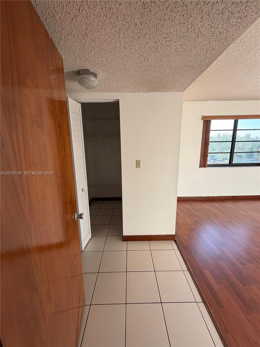 A room with wood flooring features a doorway leading to a tiled walk-in closet — 605 NW 72nd Ave # 509, Miami FL 33126, MIAMI, FL