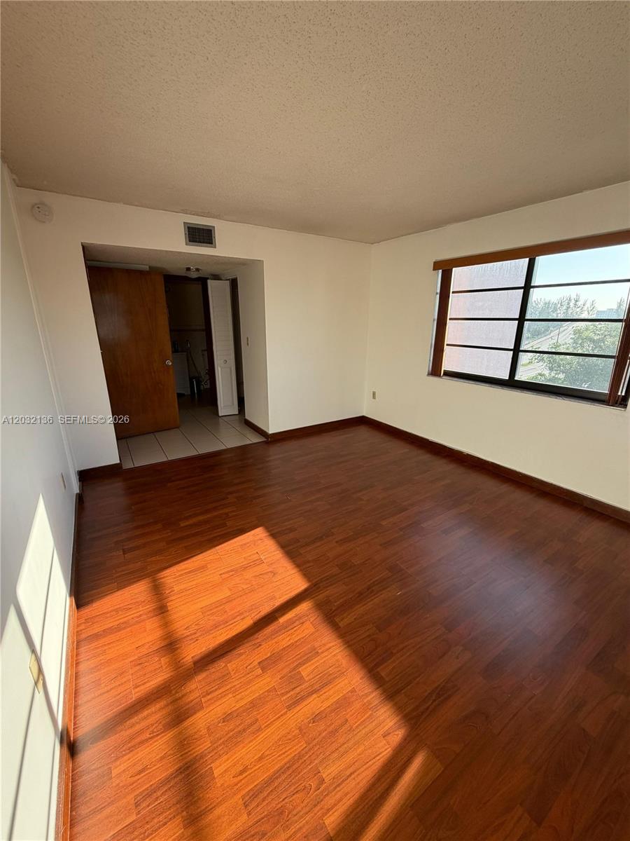 An empty room features wood-look flooring, white walls, and a large window — 605 NW 72nd Ave # 509, Miami FL 33126, MIAMI, FL