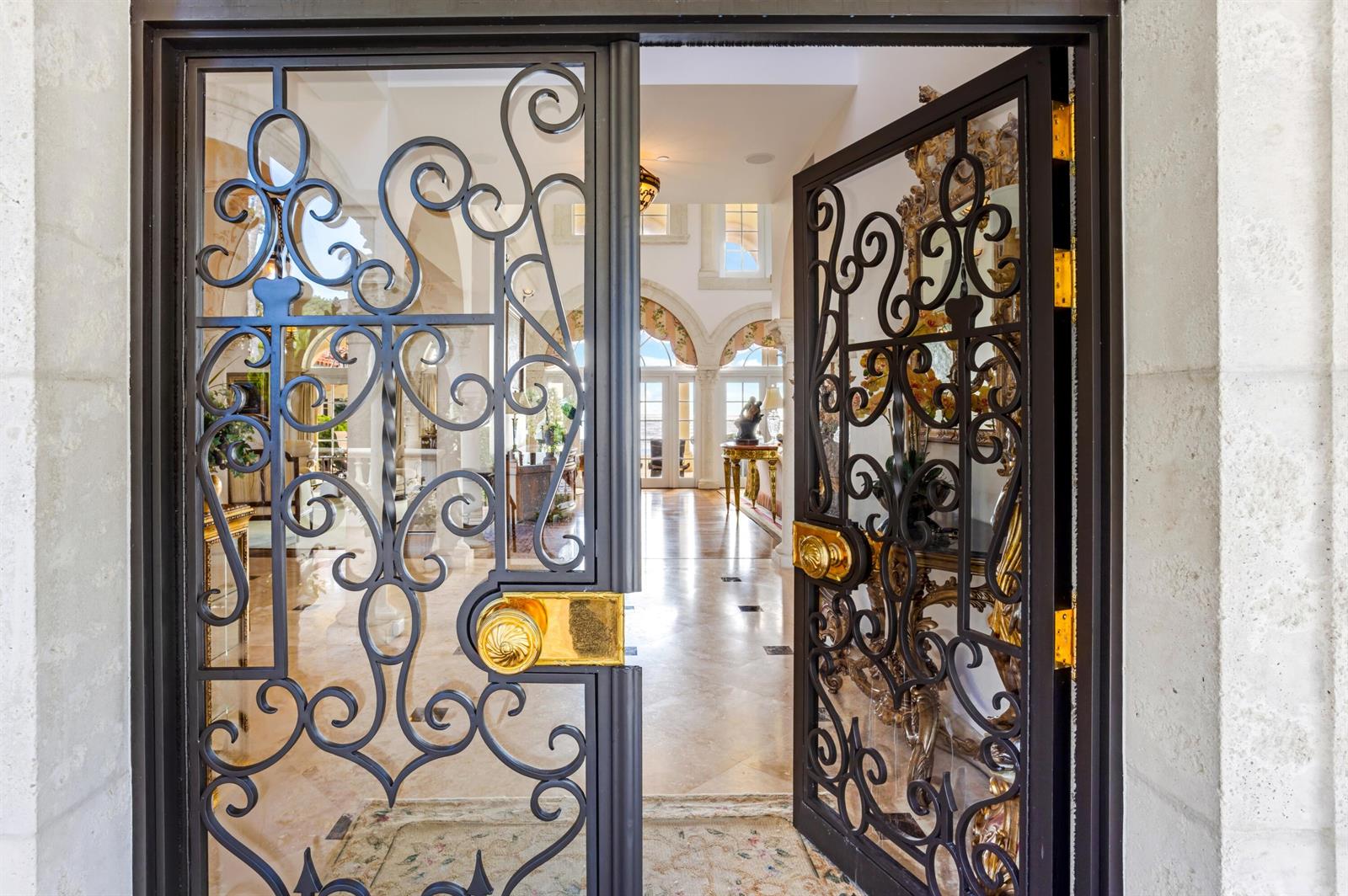 An open wrought iron double door reveals a bright, tiled foyer with arched architectural details — 6133 N Ocean Boulevard, Ocean Ridge FL 33435, OCEAN RIDGE, FL
