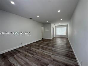 An empty room with light gray walls, recessed lighting, and dark wood-look laminate flooring — 8201 Abbott Ave # 2, Miami Beach FL 33141, MIAMI BEACH, FL