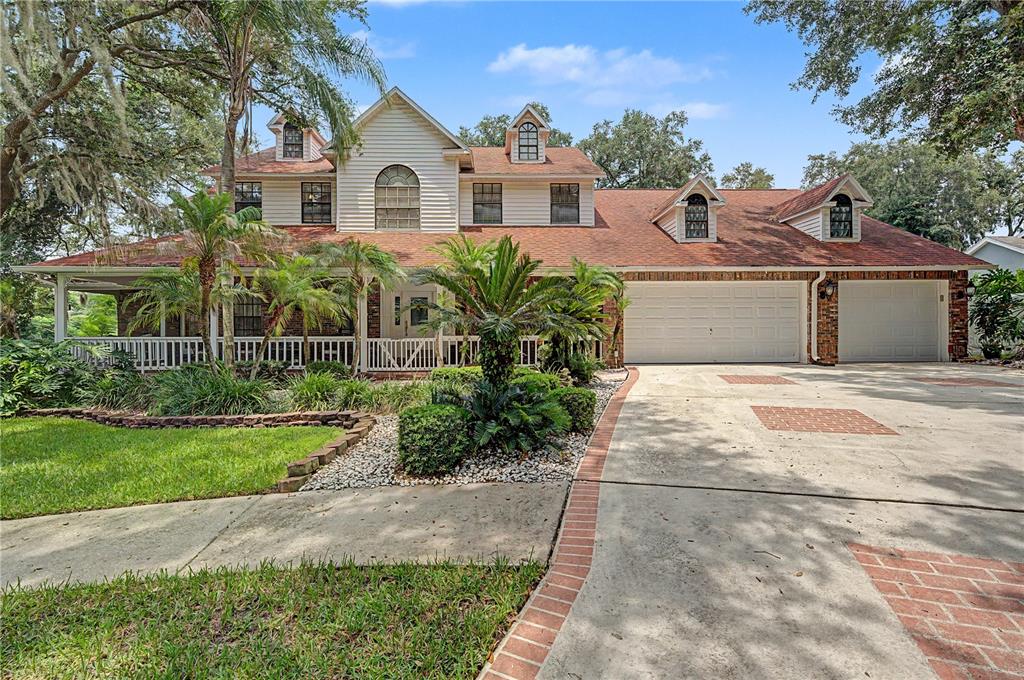 A living room with high ceilings, a brick fireplace, large windows, and a leather sectional sofa — 2004 OAKWOOD KNOLL COURT, VALRICO, FL