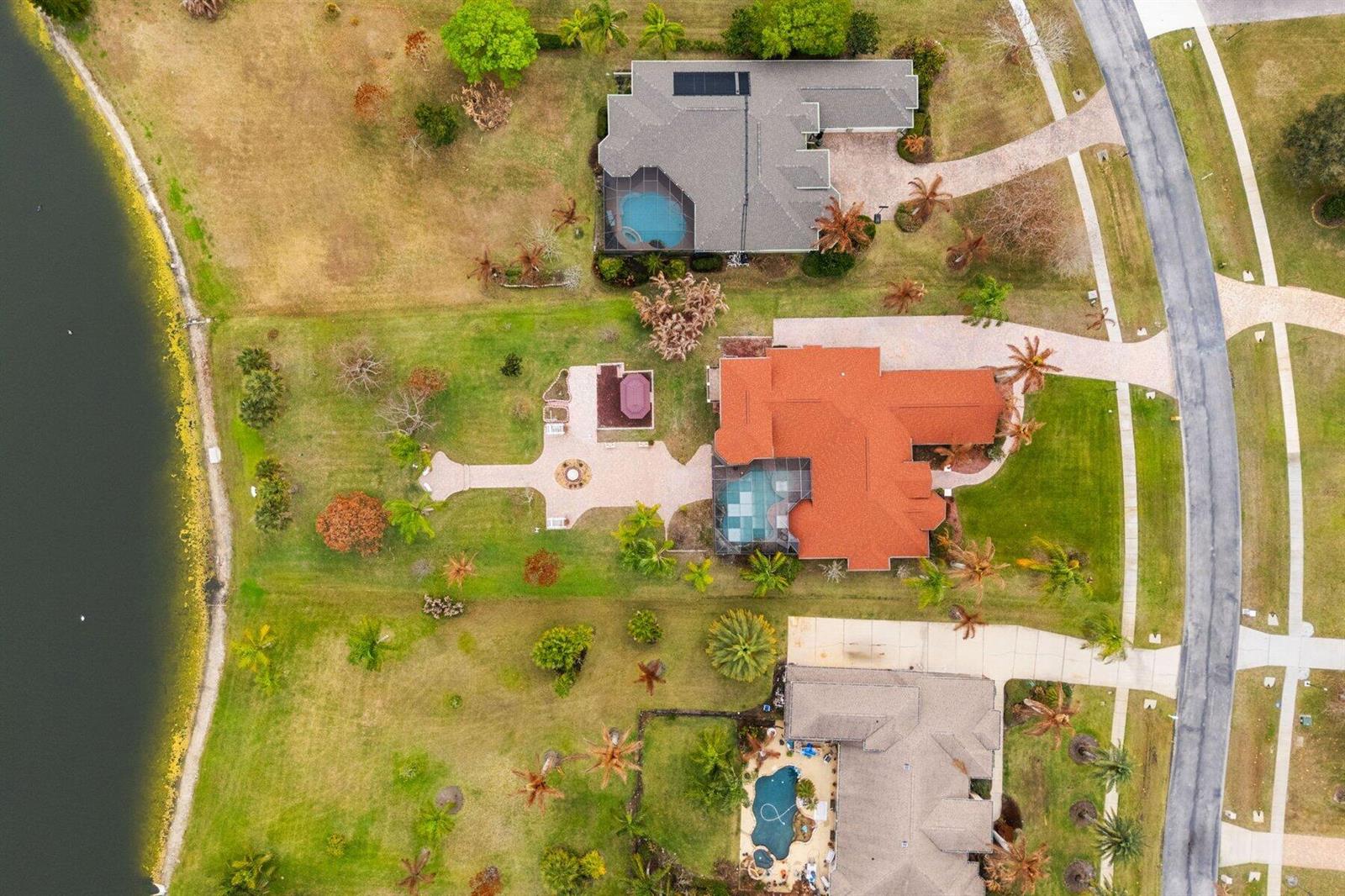 Aerial view of three suburban houses with pools and landscaped yards bordering a lake — MERRITT ISLAND, FL