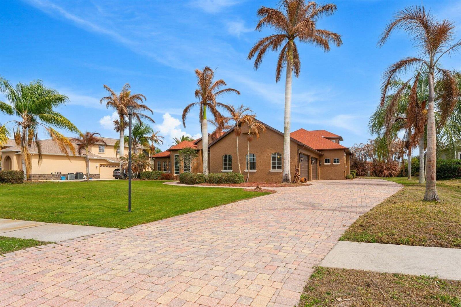 A brown house with a red roof and a paved driveway surrounded by palm trees — MERRITT ISLAND, FL