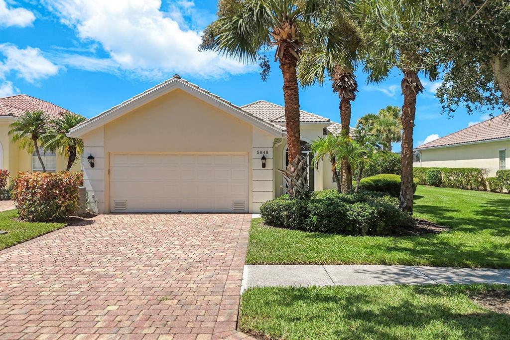 A single-story house with a paved driveway, a two-car garage, and palm trees — 5848 FERRARA DRIVE, SARASOTA, FL