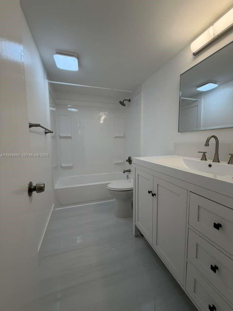 A bathroom features a white vanity, a mirror, and a shower-tub combination with white walls — 301 SE 3rd St # 109, Dania Beach FL 33004, DANIA BEACH, FL