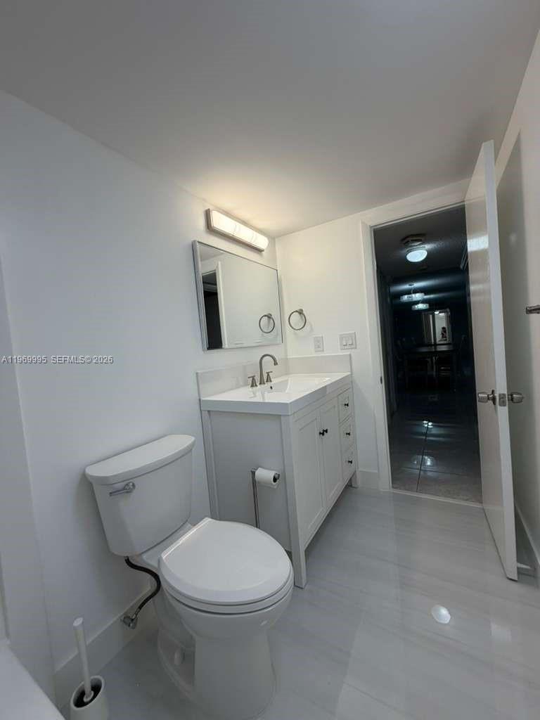 A modern bathroom features a white vanity, a toilet, and light-colored tile flooring — 301 SE 3rd St # 109, Dania Beach FL 33004, DANIA BEACH, FL