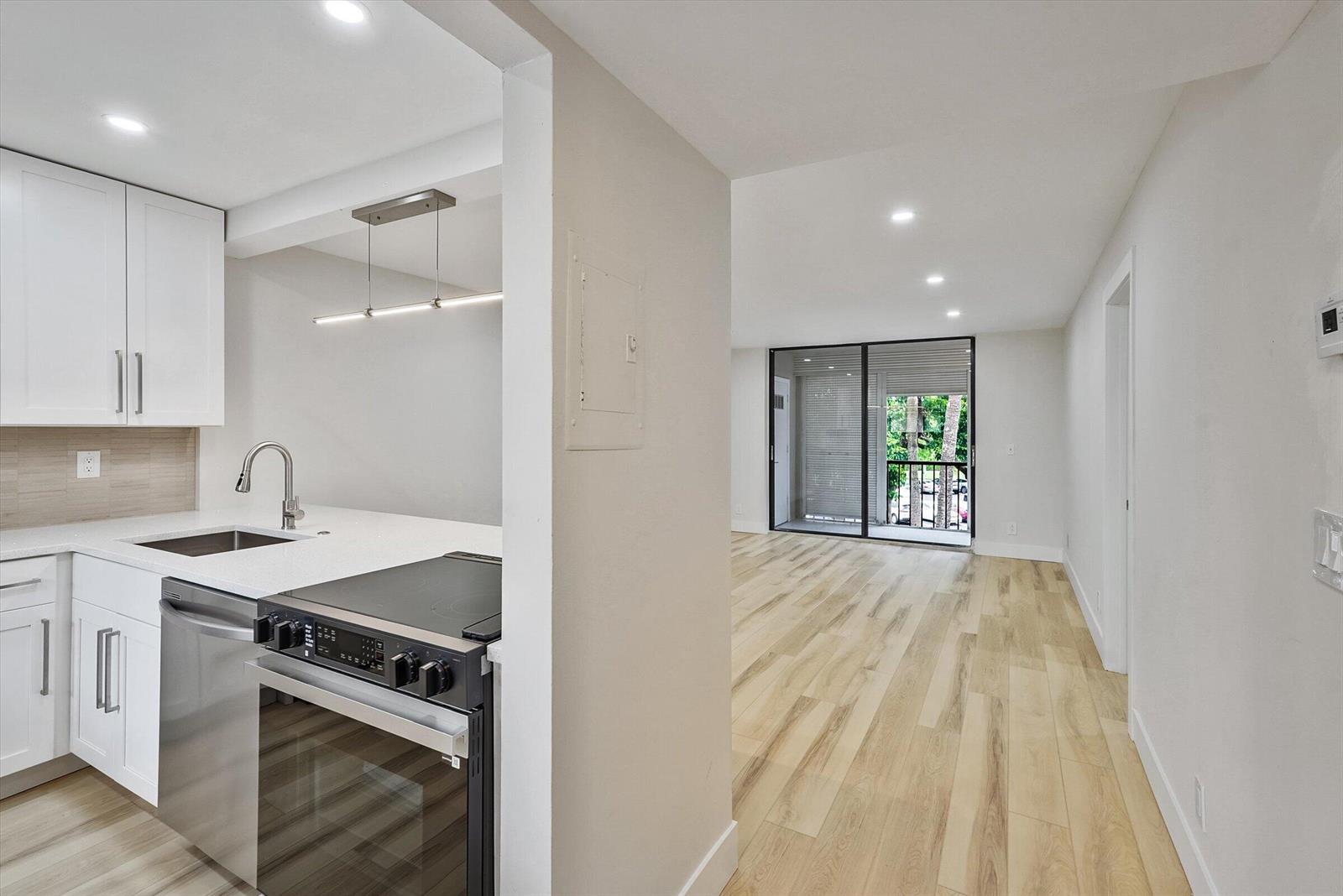 A modern kitchen with white cabinets and stainless steel appliances opens into a living area — 5220 Las Verdes Circle # 321, Delray Beach FL 33484, DELRAY BEACH, FL