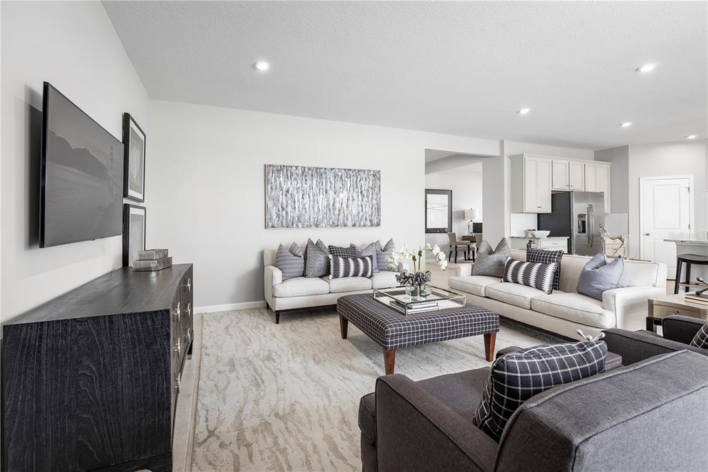 A living room features light-colored sofas, a plaid ottoman, and a dark wood media console — 9816 PINE MILL COURT, CLERMONT, FL