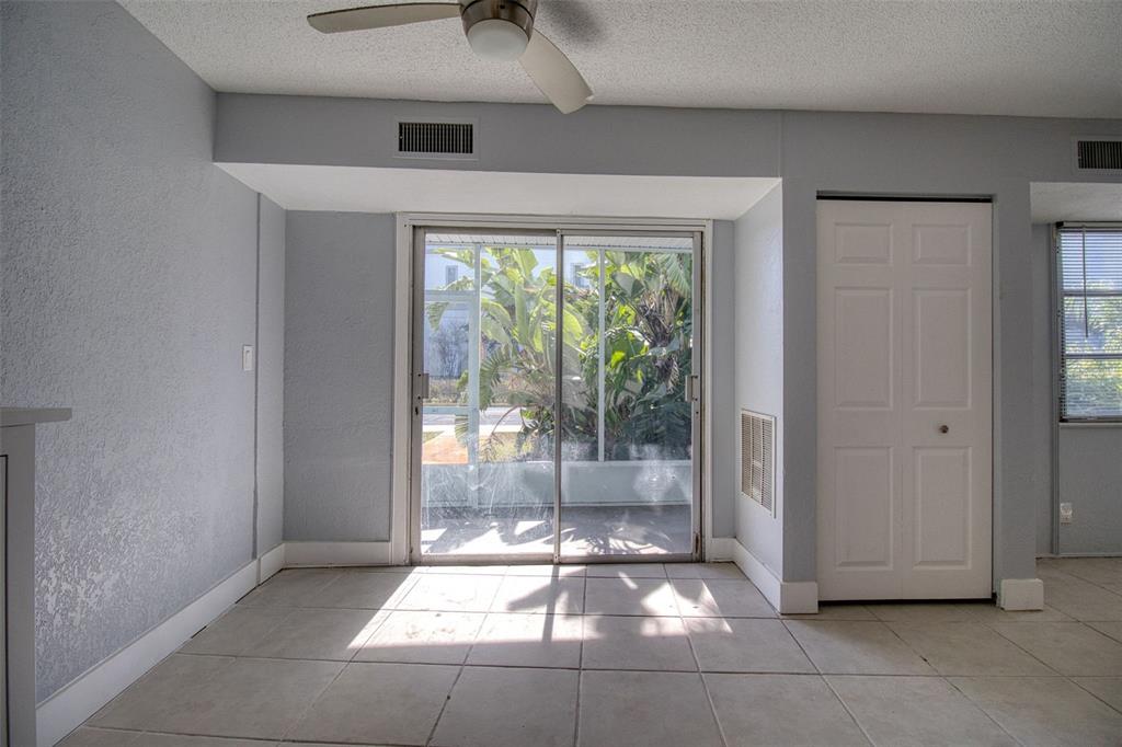An empty room with light-colored tile flooring, a ceiling fan, and sliding glass patio doors — 3315 58TH AVENUE S UNIT 112, ST PETERSBURG, FL