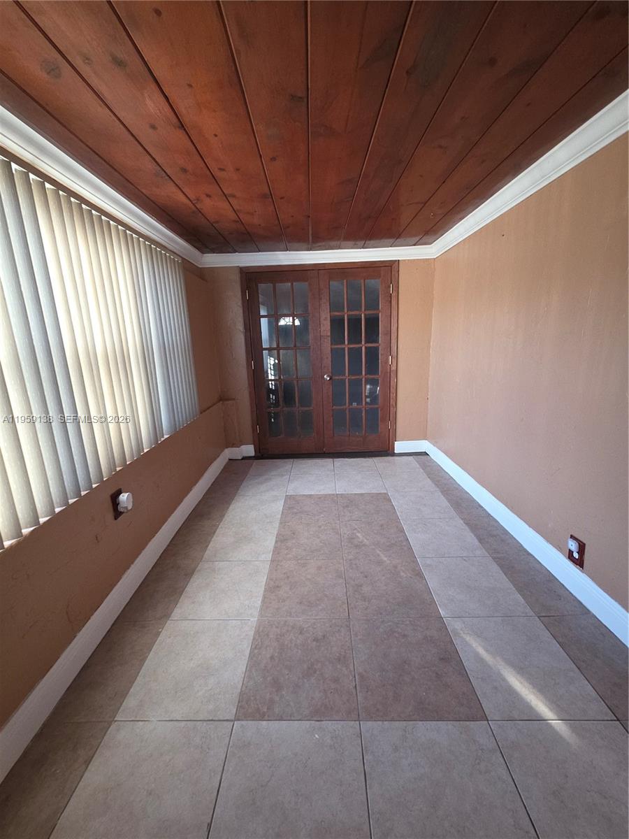 A sunroom features a wood-paneled ceiling, tiled flooring, and French doors — 2401 NW 56th St, Miami FL 33142, MIAMI, FL
