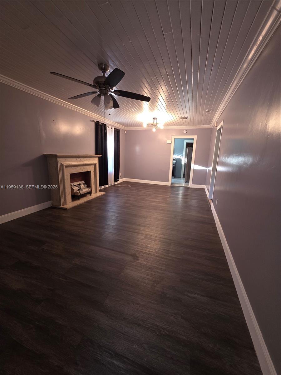 A living room features a fireplace, dark wood-look flooring, and a white beadboard ceiling — 2401 NW 56th St, Miami FL 33142, MIAMI, FL