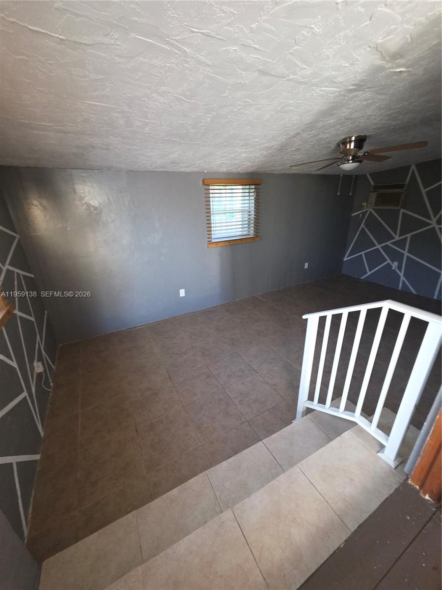An interior room features gray walls with geometric white accents, tile flooring, and a ceiling fan — 2401 NW 56th St, Miami FL 33142, MIAMI, FL