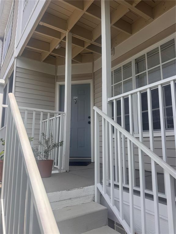 A multi-story apartment building with screened balconies, exterior staircases, and palm trees in front — 850 S TAMIAMI TRAIL UNIT 224, SARASOTA, FL