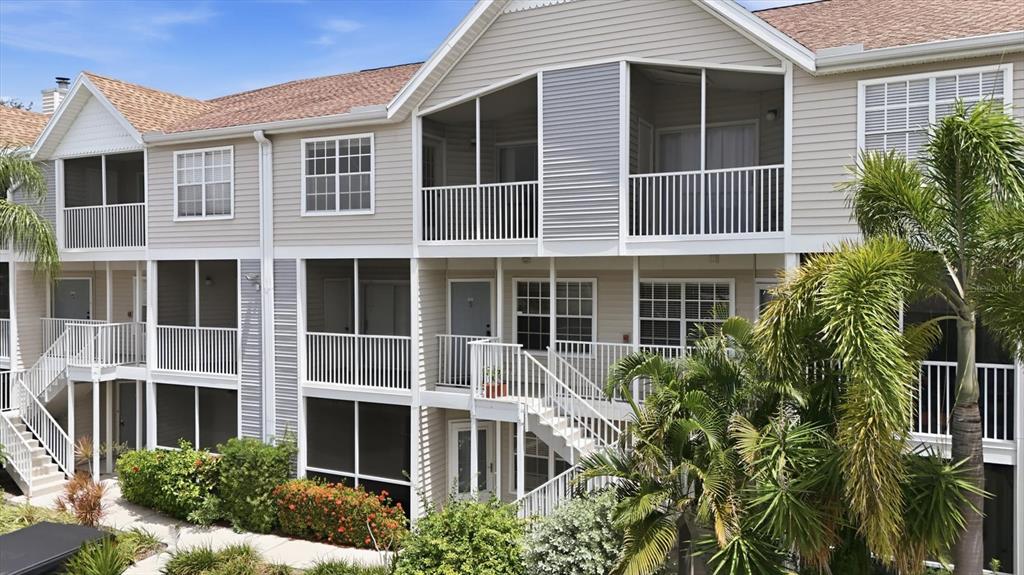A multi-story apartment building with tan siding, screened-in balconies, and exterior staircases — 850 S TAMIAMI TRAIL UNIT 224, SARASOTA, FL