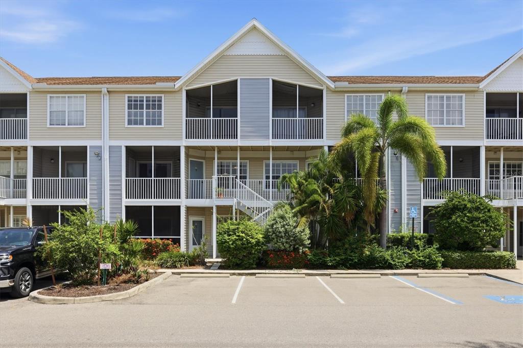 A three-story apartment building with screened balconies and a parking lot in the foreground — 850 S TAMIAMI TRAIL UNIT 224, SARASOTA, FL