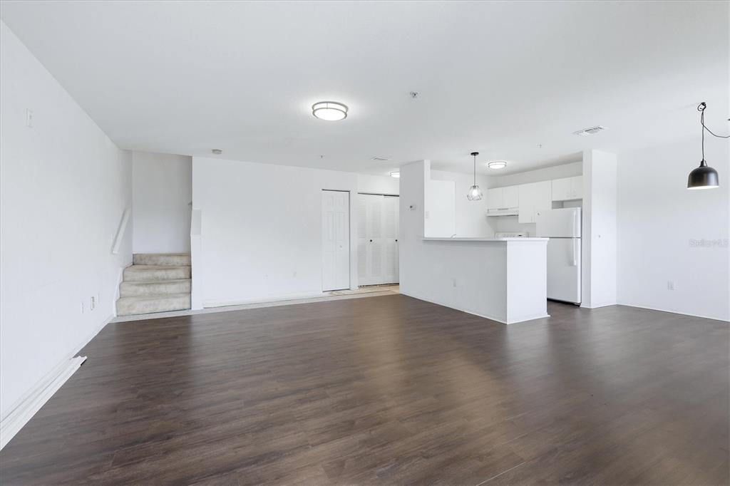 An open-concept living area with dark wood-look flooring, a kitchen, and a carpeted staircase — 850 S TAMIAMI TRAIL UNIT 224, SARASOTA, FL