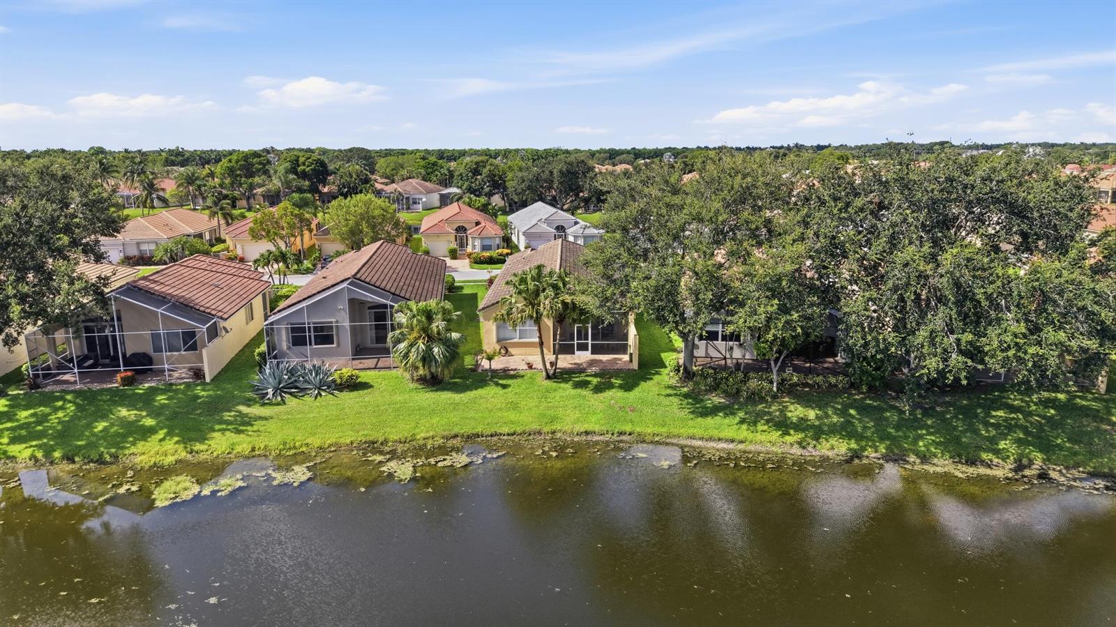 An aerial view shows several suburban houses with screened-in lanais bordering a lake — 7229 Cataluna Circle, Delray Beach FL 33446, DELRAY BEACH, FL
