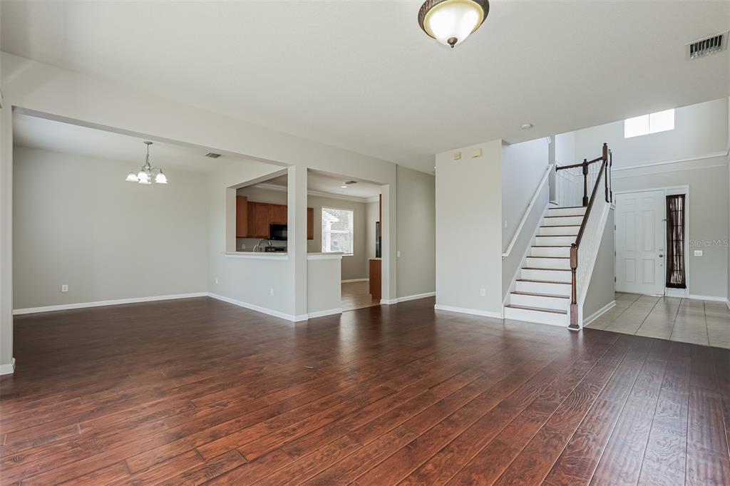 An open-concept living area features dark wood flooring, a staircase, and a kitchen pass-through window — 13955 CRATER CIRCLE, HUDSON, FL