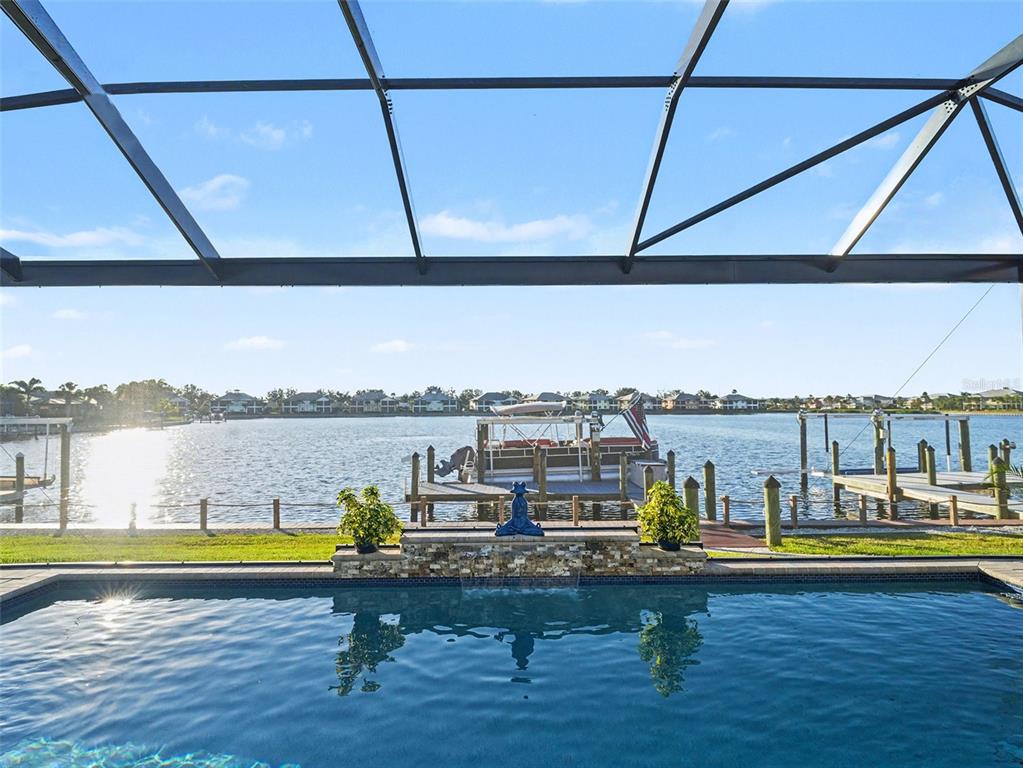 A swimming pool with a stone water feature overlooks a lake with boat docks — 1018 OVERLOOK COURT, BRADENTON, FL