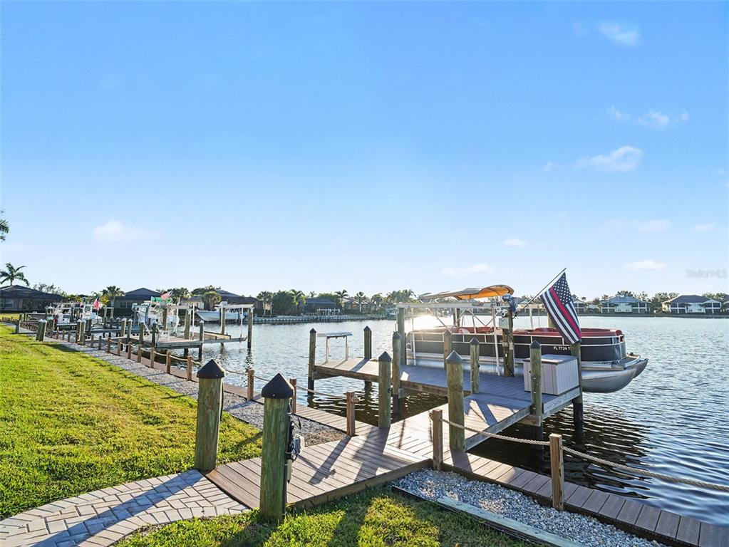 A wooden dock extends into a canal with several boats moored along the shoreline — 1018 OVERLOOK COURT, BRADENTON, FL