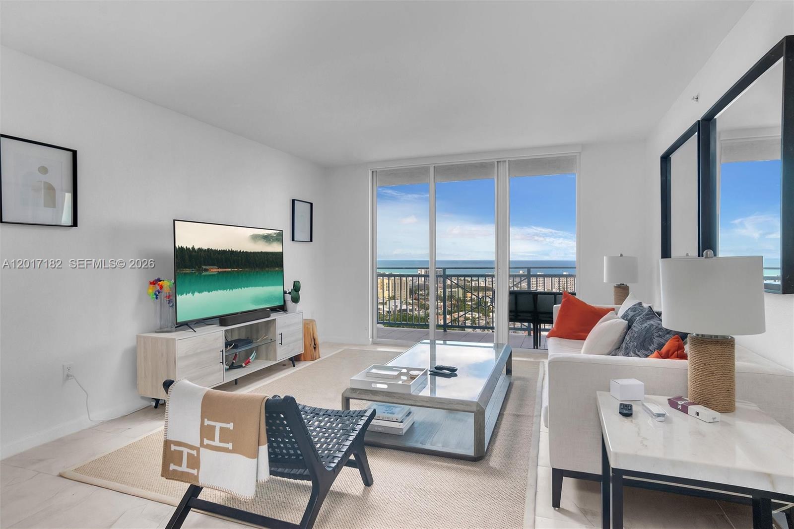 A bright living room features a sofa, coffee table, television, and a balcony with ocean views — 90 Alton Rd # 2303, Miami Beach FL 33139, MIAMI BEACH, FL