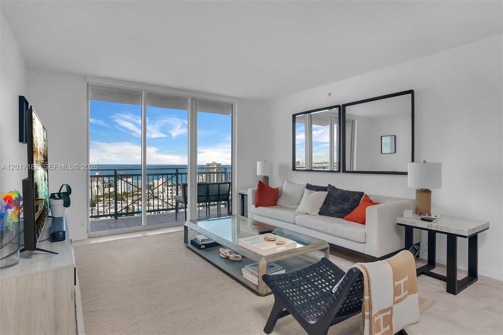 A living room features a white sofa, glass coffee table, and balcony with ocean views — 90 Alton Rd # 2303, Miami Beach FL 33139, MIAMI BEACH, FL