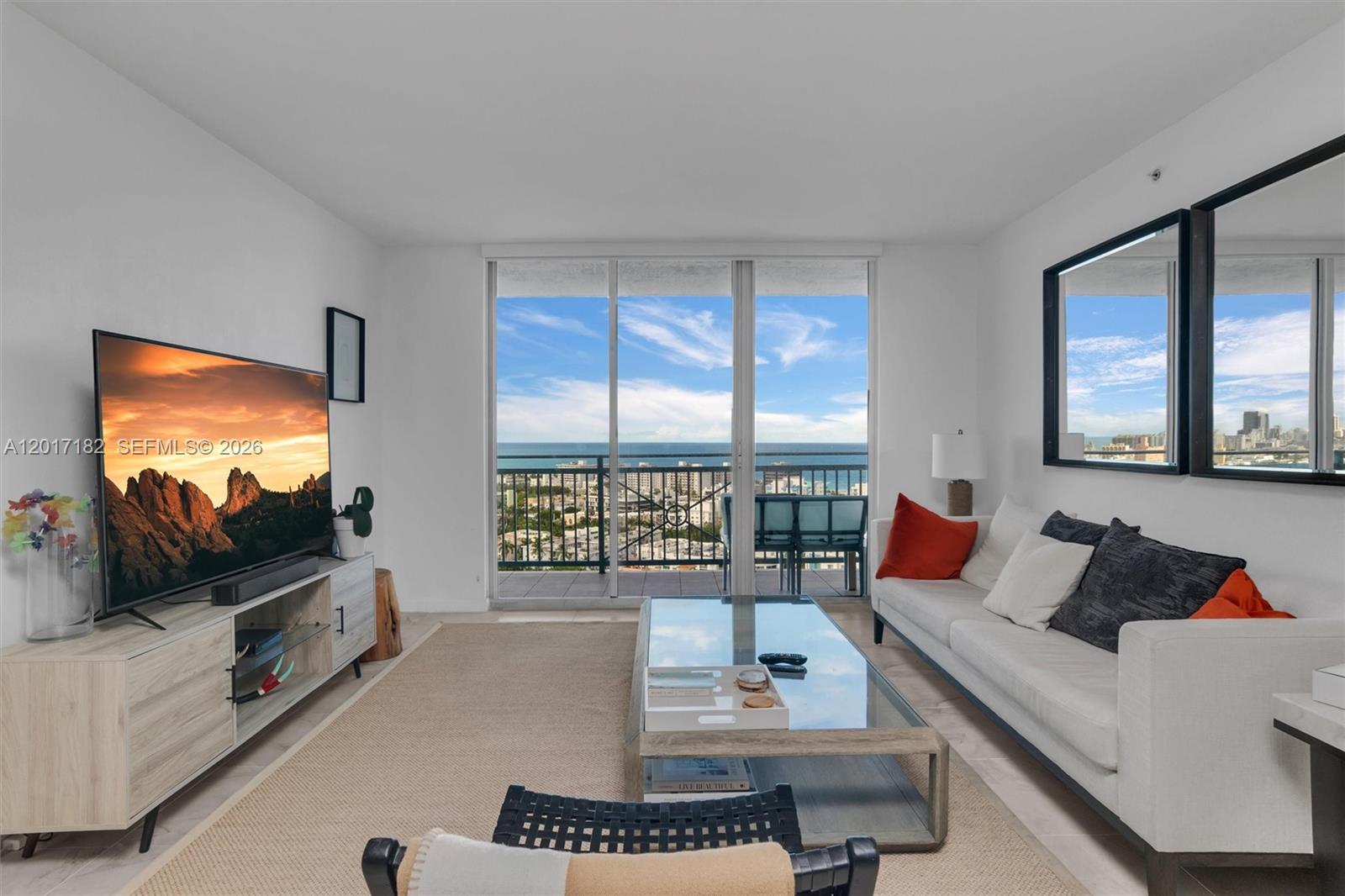 A living room features a television, sofa, coffee table, and a balcony with ocean views — 90 Alton Rd # 2303, Miami Beach FL 33139, MIAMI BEACH, FL