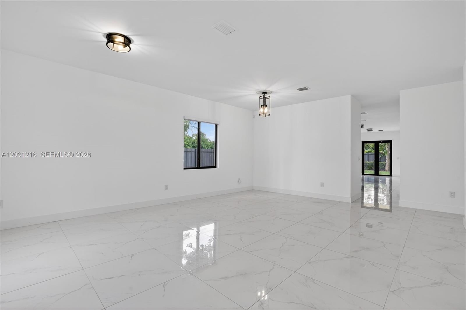 A bright, empty room features white walls, large marble-look floor tiles, and two light fixtures — 8500 SW 198th St, Cutler Bay FL 33189, CUTLER BAY, FL