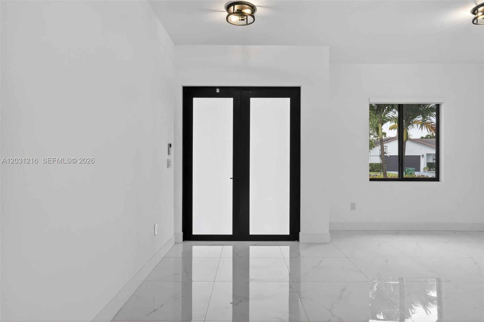A bright room features white walls, large marble-style floor tiles, and black-framed double entry doors — 8500 SW 198th St, Cutler Bay FL 33189, CUTLER BAY, FL