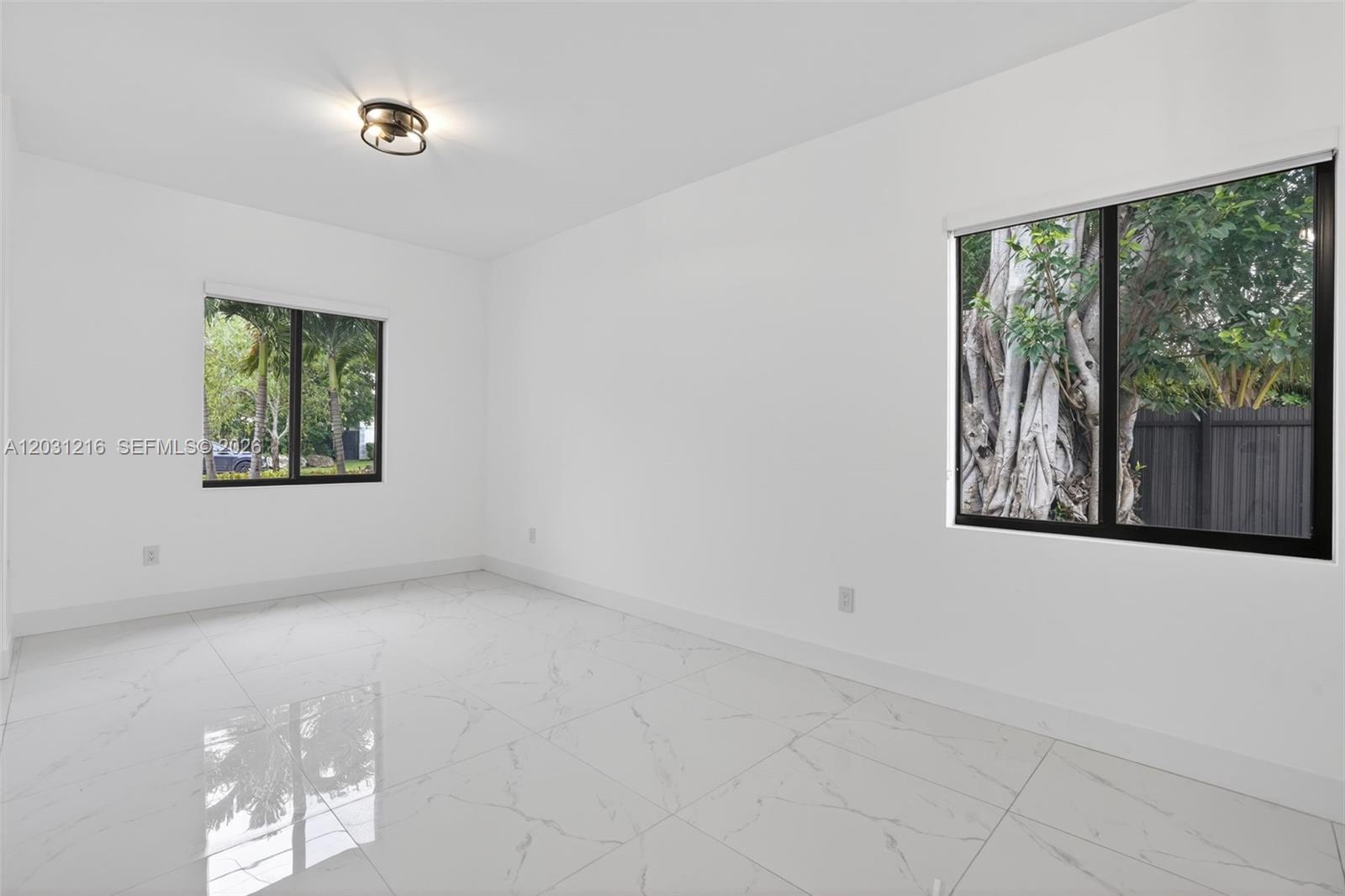 A bright, empty room features white walls, large windows, and glossy white marble-patterned tile flooring — 8500 SW 198th St, Cutler Bay FL 33189, CUTLER BAY, FL