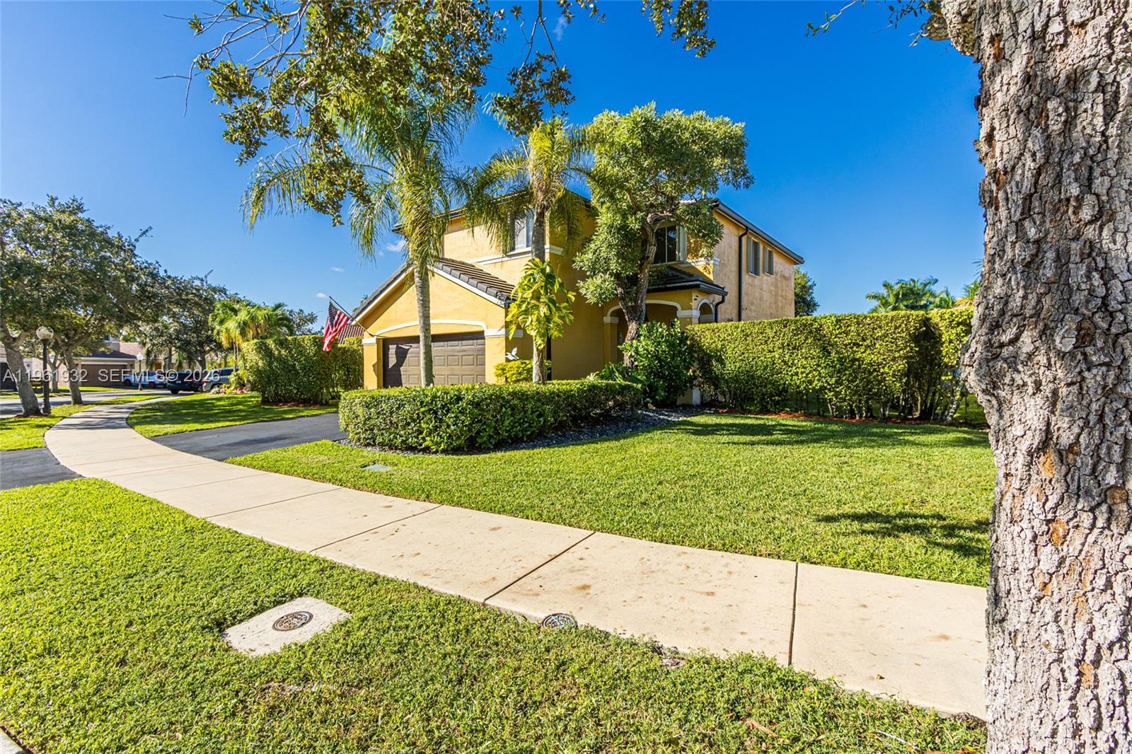 A yellow two-story house with a garage and a hedge-lined front yard — 1280 Majesty Ter, Weston FL 33327, WESTON, FL