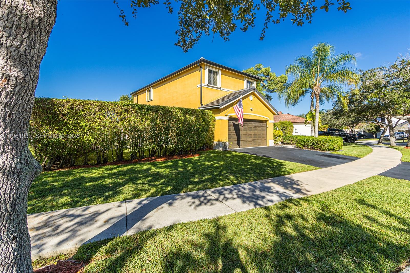 A two-story yellow house with a brown garage door and a manicured hedge — 1280 Majesty Ter, Weston FL 33327, WESTON, FL