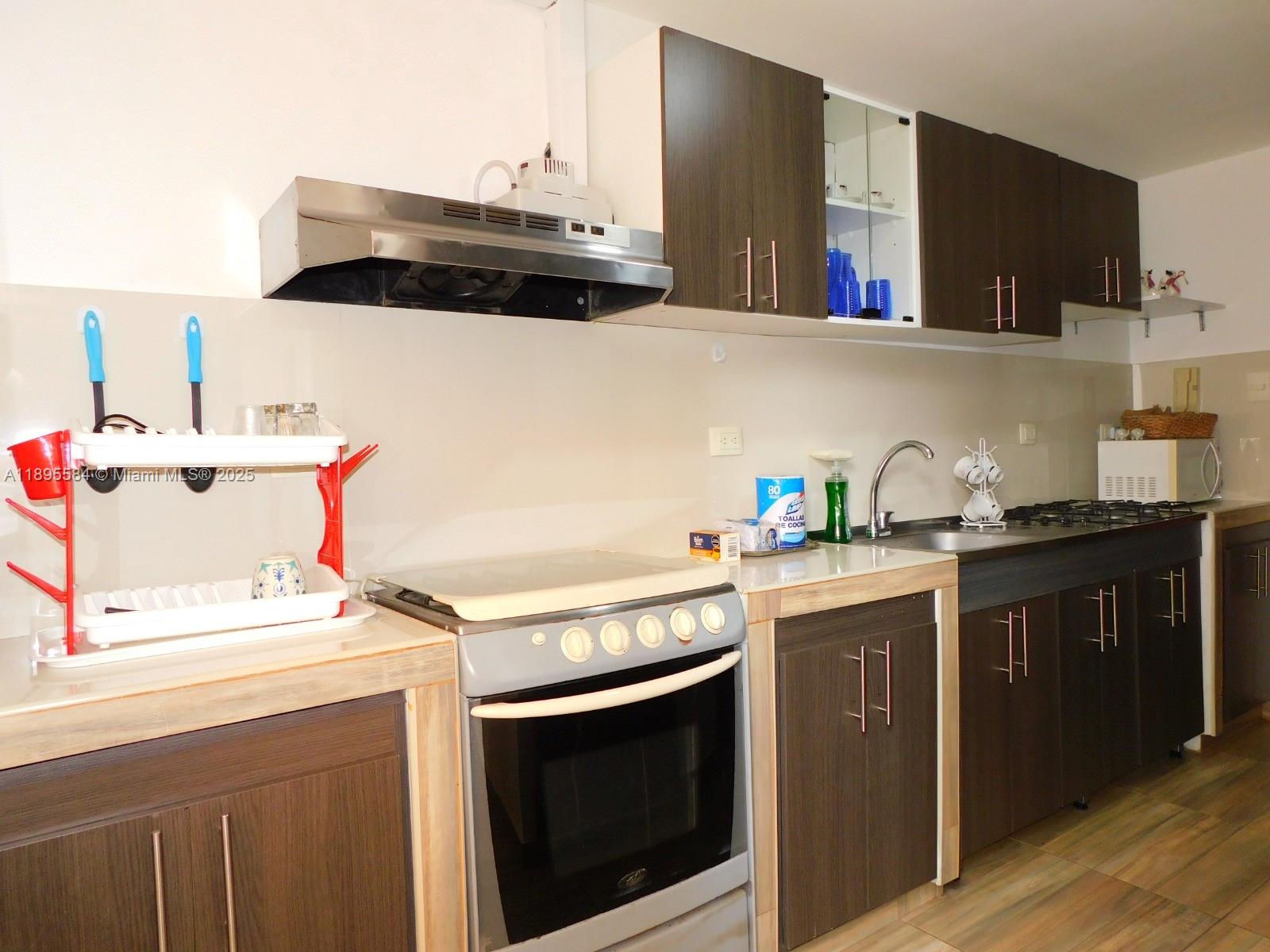 A kitchen features dark wood cabinets, a stainless steel range, and a light-colored countertop — 77-53 57 Ave # 2, xx, xx