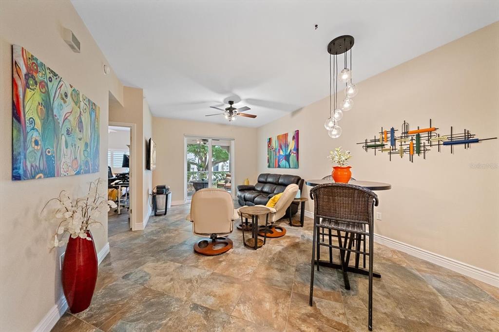 A living and dining area features tile flooring, a ceiling fan, and a glass sliding door — 4244 CENTRAL SARASOTA PARKWAY UNIT 714, SARASOTA, FL
