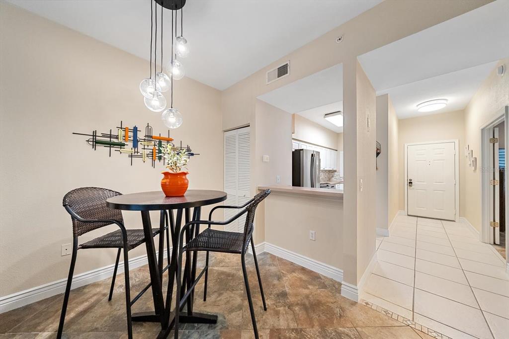 A dining area features a round table, two chairs, a modern light fixture, and tile flooring — 4244 CENTRAL SARASOTA PARKWAY UNIT 714, SARASOTA, FL