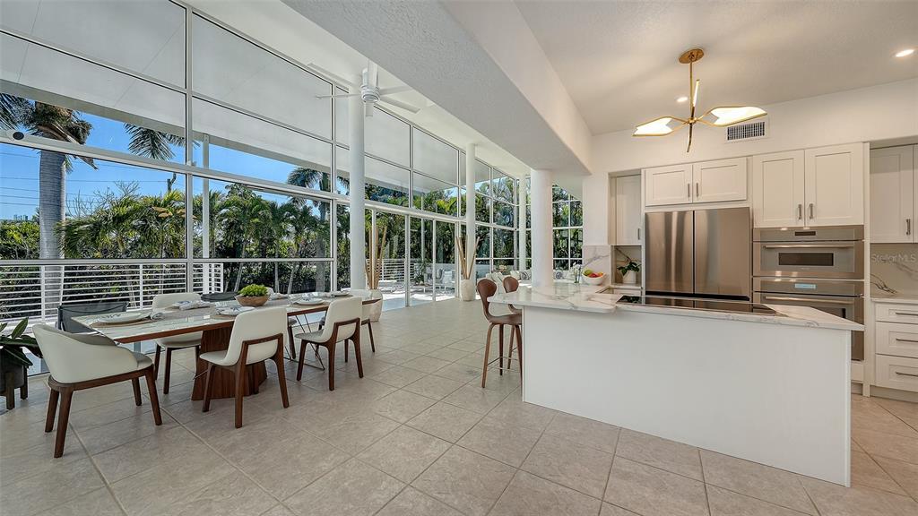 A modern open-concept kitchen and dining area with floor-to-ceiling windows overlooking a patio — 1168 WESTWAY DRIVE, SARASOTA, FL