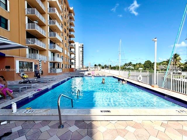 A swimming pool sits on a patio next to a multi-story apartment building — 2450 NE 135th St # 704, North Miami FL 33181, NORTH MIAMI, FL