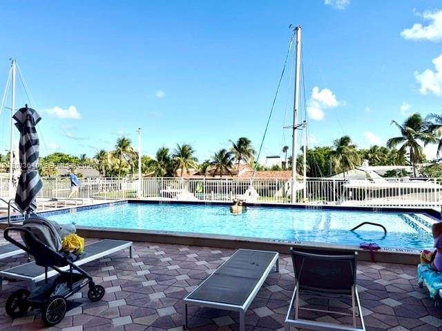 A swimming pool overlooks a marina with palm trees under a bright blue sky — 2450 NE 135th St # 704, North Miami FL 33181, NORTH MIAMI, FL