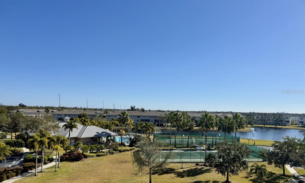 An elevated view of a residential complex featuring tennis courts, a pool, and a lake — 7194 KEY HAVEN ROAD UNIT 504, SEMINOLE, FL