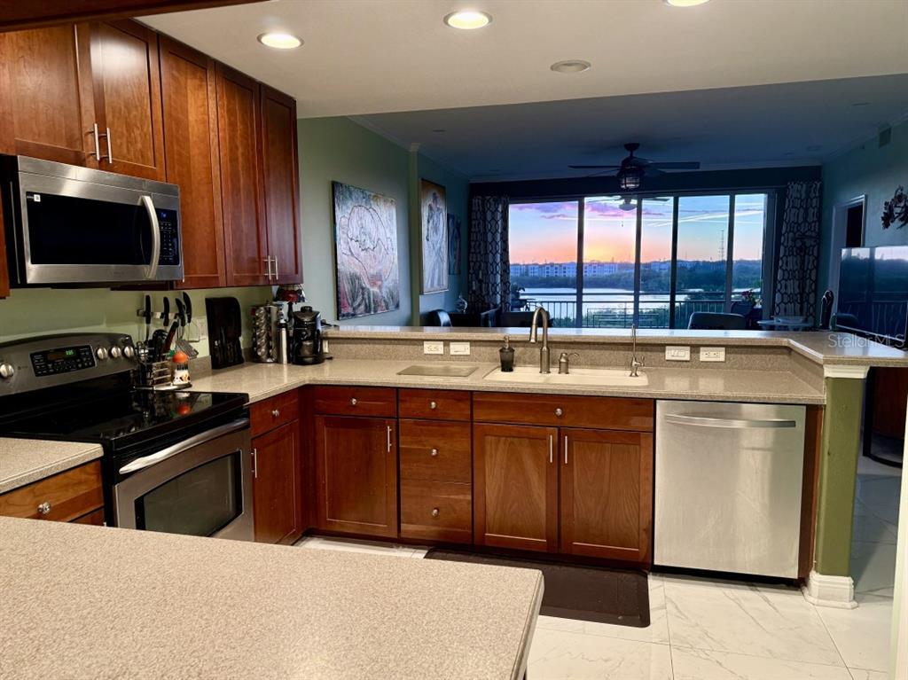 A kitchen with wood cabinets, stainless steel appliances, and a view of a lake outside — 7194 KEY HAVEN ROAD UNIT 504, SEMINOLE, FL
