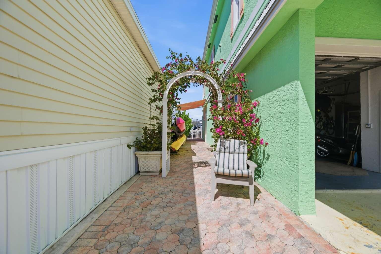 A paved walkway between two houses features a white arbor, a chair, and potted plants — 10701 S Ocean Drive # 817, Jensen Beach FL 34957, JENSEN BEACH, FL