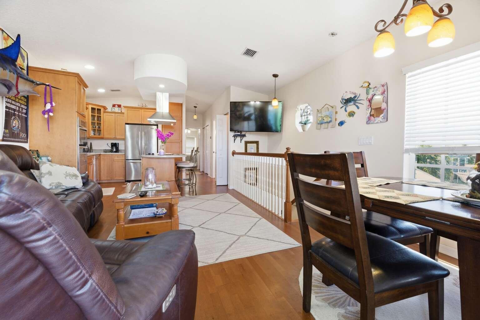 An open-concept living and dining area features wood flooring, wooden cabinetry, and a staircase railing — 10701 S Ocean Drive # 817, Jensen Beach FL 34957, JENSEN BEACH, FL