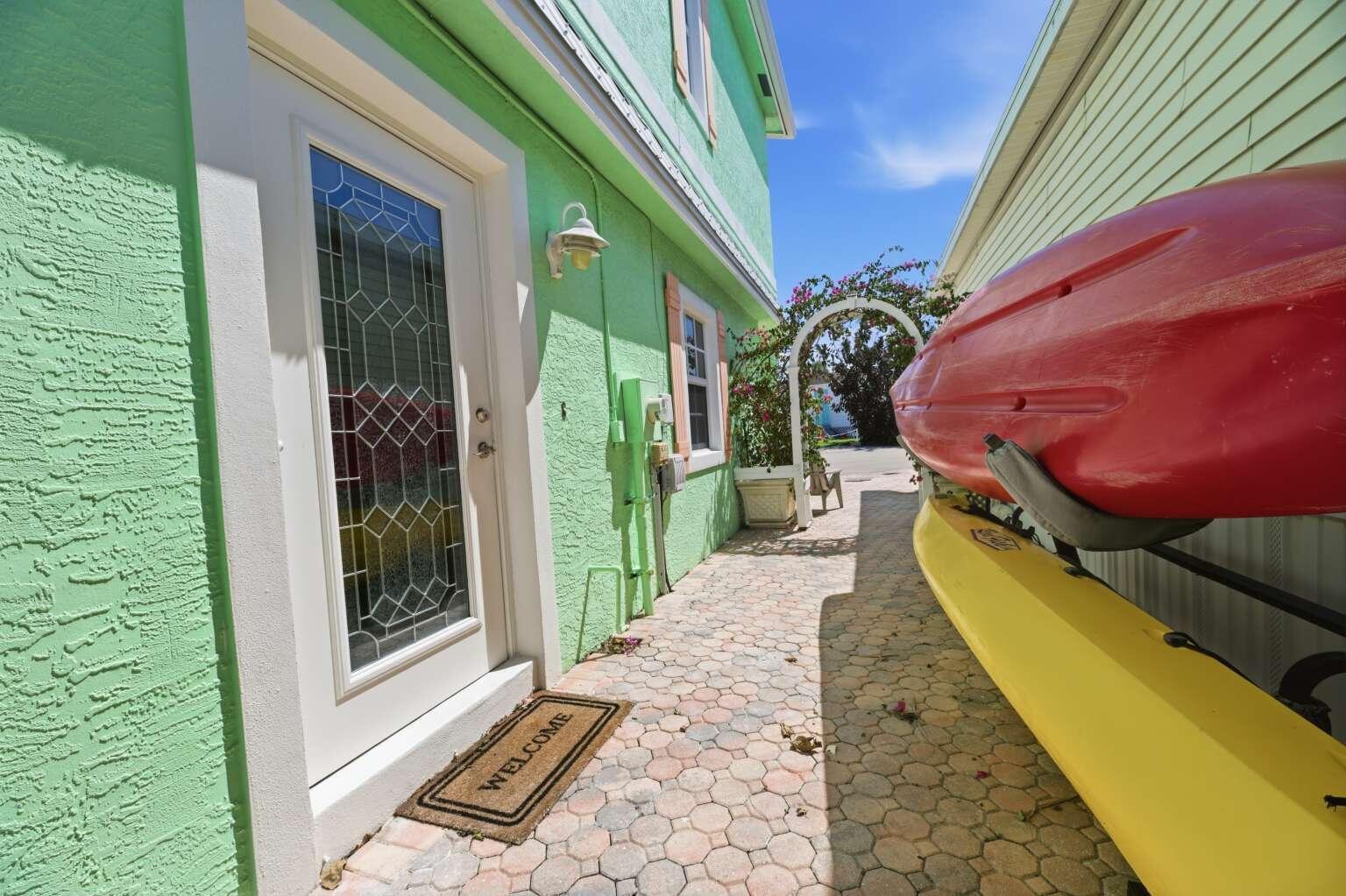 A side walkway with a green house, a welcome mat, and kayaks stored on the wall — 10701 S Ocean Drive # 817, Jensen Beach FL 34957, JENSEN BEACH, FL