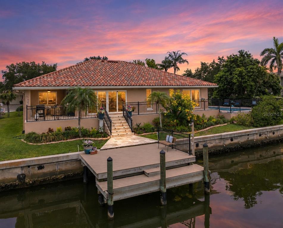 An elevated waterfront house with a tiled roof, a wooden dock, and a swimming pool — 2001 ILLINOIS AVE NE, ST PETERSBURG, FL