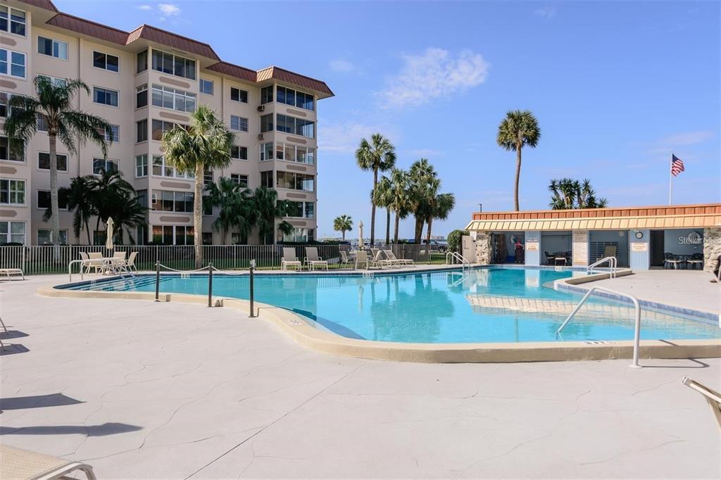A swimming pool sits in front of a multi-story apartment building with palm trees — 632 EDGEWATER DRIVE UNIT 139, DUNEDIN, FL