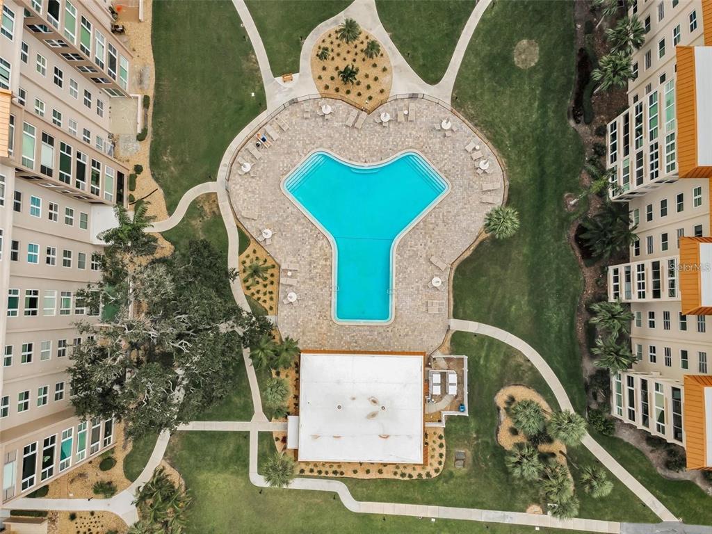 An aerial view shows a Y-shaped swimming pool surrounded by a patio and apartment buildings — 632 EDGEWATER DRIVE UNIT 139, DUNEDIN, FL